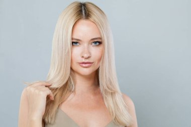 Güzel, güler yüzlü, güzel saçlı, mutlu bir kadın model. Saf parlak tenli ve gri arka planda sarı saçlı güzel bir kadının stüdyo fotoğrafı.