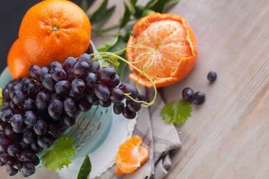 Gri ahşap arka planda koyu üzüm ve portakal meyvesi. Organik meyve seti