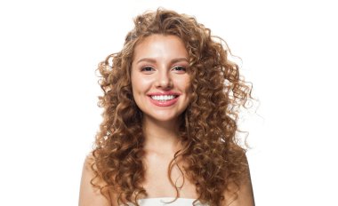 Kızıl saçlı, uzun kıvırcık saçlı ve beyaz arka planda poz veren temiz, taze tenli mutlu bir model. Stüdyo moda güzellik portresi