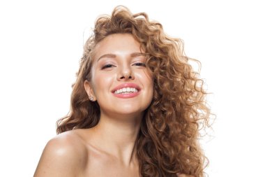 Kızıl saçlı, uzun kıvırcık kızıl saçlı ve beyaz arka planda poz veren temiz, taze tenli heyecanlı bir manken. Stüdyo moda güzellik portresi