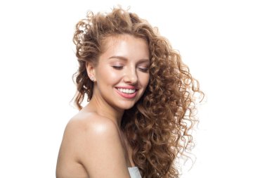 Kaygısız kızıl saçlı, uzun kıvırcık kızıl saçlı ve beyaz arka planda poz veren temiz, taze tenli bir manken. Stüdyo moda güzellik portresi