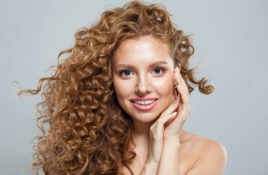 Kızıl saçlı, uzun kıvırcık saçlı ve beyaz arka planda poz veren güzel bir manken. Stüdyo moda güzellik portresi