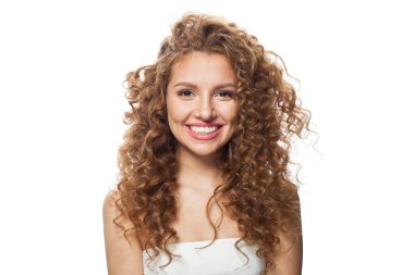 Uzun kıvırcık kızıl saçlı ve beyaz arka planda poz veren temiz, taze tenli neşeli bir model. Stüdyo moda güzellik portresi