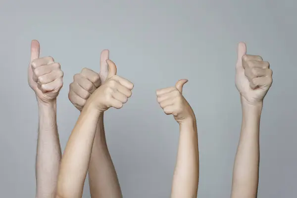 Many hands showing thumb up signs on white background