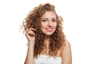 Doğal makyajlı, parlak ciltli ve uzun kıvırcık saçlı neşeli ve sağlıklı bir model. Saç bakımı, cilt bakımı, kozmetoloji ve stil konsepti