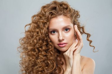 Doğal makyajlı, parlak berrak ciltli ve uzun kıvırcık saçlı sağlıklı bir model. Saç bakımı, cilt bakımı, kozmetoloji ve stil konsepti