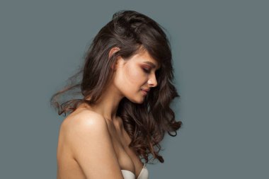 Güzel, neşeli, esmer, doğal makyajlı, sağlıklı, temiz tenli, koyu dalgalı saçlı, stüdyo moda güzellik portresi olan bir kadın. Cilt bakımı, saç bakımı ve kozmetik konsepti