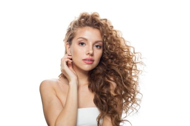 Güzel, sağlıklı, doğal makyajlı, parlak ciltli, uzun kıvırcık saçlı, kulağına beyaz arka planda elmas küpeler takan bir kadın.