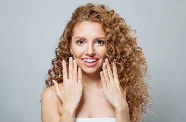 Şok olmuş sağlıklı model, doğal makyaj, parlak berrak cilt ve uzun kıvırcık saç stili. Saç bakımı, cilt bakımı, kozmetoloji ve stil konsepti