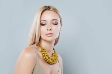 Uzun renkli saçları ve sağlıklı deri portresi olan zarif, genç bir bayan model. Sarışın kadın gri stüdyo arka planındaki kameraya bakıyor.