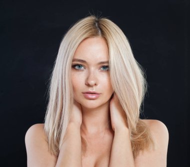 Uzun renkli saçları ve sağlıklı deri portresi olan genç ve güzel bir bayan manken. Sarışın kadın gri stüdyo arka planındaki kameraya bakıyor.