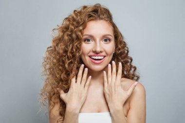 Heyecanlı, sağlıklı, doğal makyajlı, parlak ve uzun kıvırcık saçlı bir model. Saç bakımı, cilt bakımı, kozmetoloji ve stil konsepti