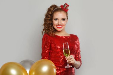 Makyajlı, saç stili, kırmızı, parlak pullu, parti balonları, sürpriz, hediyeler ve Noel tatili geçmişi olan büyüleyici mutlu bir kadın.