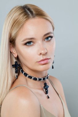 Uzun renkli saçları ve sağlıklı deri portresi olan genç ve güzel bir bayan manken. Sarışın kadın gri stüdyo arka planındaki kameraya bakıyor.