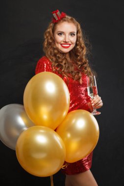 Makyajlı, saç stili, kırmızı, parlak pullu, parti balonları, sürpriz, hediyeler ve Noel tatili geçmişi olan neşeli, mutlu bir kadın.