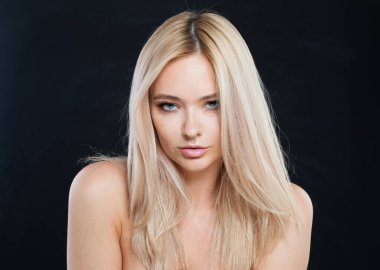 Model kadın yakından bakıyor. Taze ciltli sarışın manken ve siyah arka planda sağlıklı ipek saçlı. 