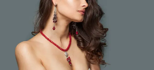 Fashion jewelry model closeup. Necklace and earring with red stones