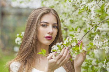 Doğal makyajlı, açık hava parkında uzun, sağlıklı kahverengi saçlı genç bir kadının moda portresi. Doğal kadın güzelliği