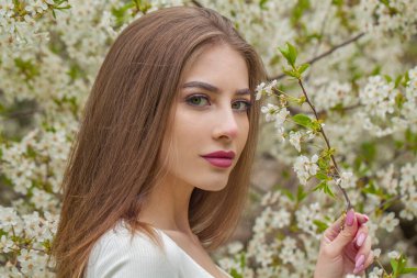 Doğal makyajlı neşeli genç bir kadın ve açık hava parkında uzun, sağlıklı kahverengi saçları var. Doğal kadın güzellik portresi.