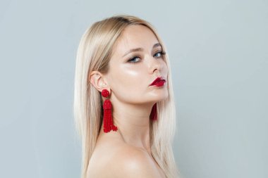 Makyajlı, uzun sarı saçlı, beyaz stüdyo duvarlı mükemmel bir genç kadın.