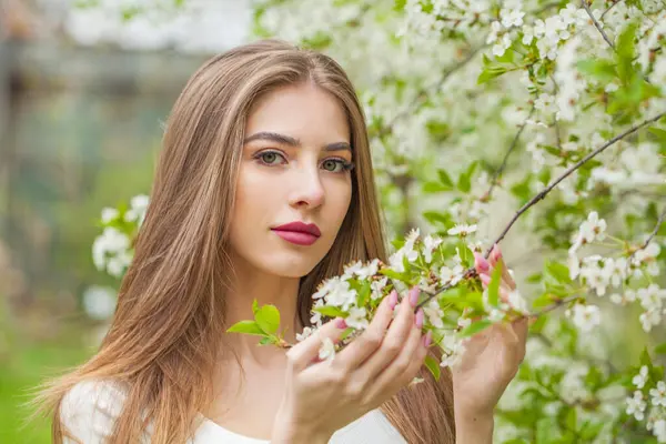Doğal makyajlı, açık hava parkında uzun, sağlıklı kahverengi saçlı genç bir kadının moda portresi. Doğal kadın güzelliği