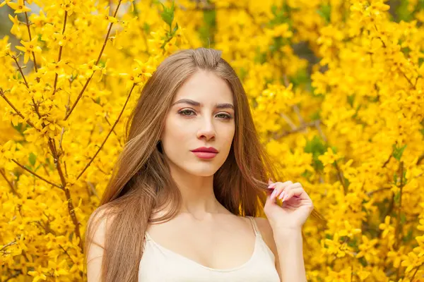 Summer young woman with natural makeup and healthy long brown hair in blossom park outdoors. Natural female beauty portrait