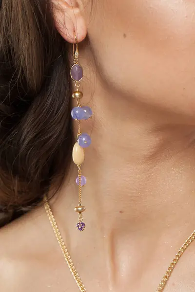 Attractive jewelry model closeup. Golden Necklace and earring with blue and purple chalcedony stones