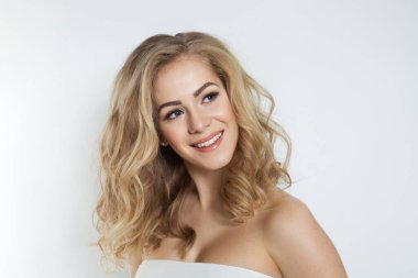 Sağlıklı, temiz tenli, uzun dalgalı saçlı, beyaz arka plana bakan güzel sarışın kadın.