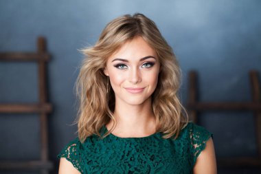 Mavi arka planda gülümseyen çekici, arkadaş canlısı bir kadın.