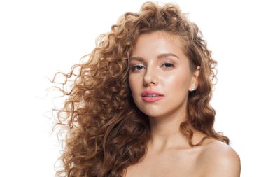 Doğal makyajlı, temiz ciltli ve beyaz arka planda dalgalı saçlı güzel bir kadın.