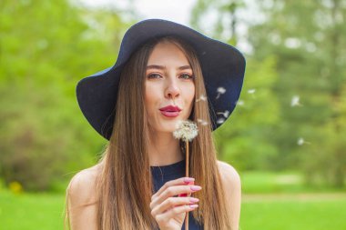 Uzun kahverengi saçlı ve çiçekli arka planda doğal makyajlı mutlu bir manken.