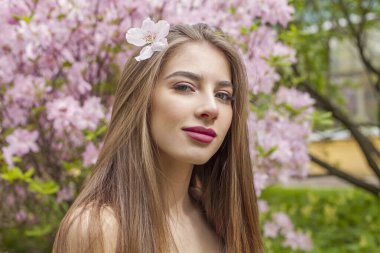 Doğal makyajlı, açık hava parkında uzun ve sağlıklı kahverengi saçlı çekici bir genç kadın. Doğal kadın güzellik portresi.