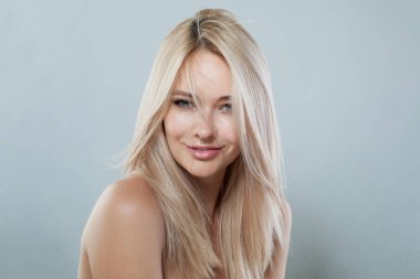 Gülümseyen, uzun sarı saç stili ve beyaz arka planda parlak cildi olan moda mankeni, stüdyo resmi. 