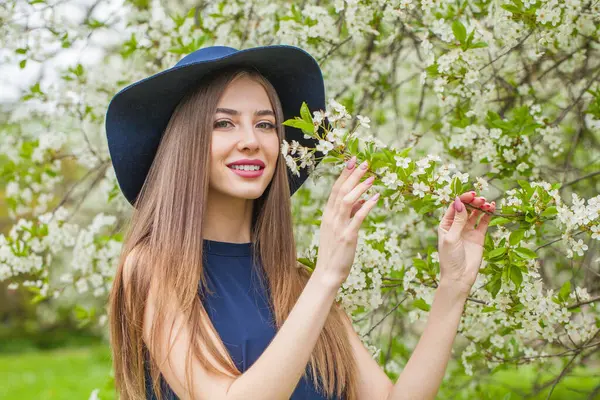 Çiçekli arka planda, uzun kahverengi saçlı ve doğal makyajlı göz alıcı bir manken.