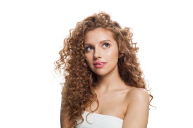 Temiz tenli, kıvırcık saçlı ve doğal makyajlı güzel bir kızıl kadın. Beyaz arkaplana bakan kadın modeli