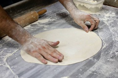 Hamur hazırlığı. Hamur, adamın ellerini un ile masaya koyuyor.