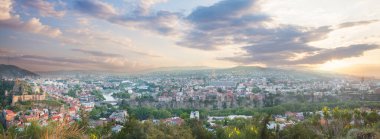 Tarihsel Tiflis 'in panoramik güzellikteki manzarası. Dağlar ve arka planda mavi bulutlu gökyüzü.