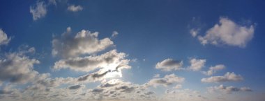 Parlak mavi gökyüzü, güneş ve beyaz bulutlar, hava durumu arka planı
