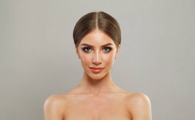 Temiz ciltli, makyajlı ve beyaz stüdyo duvarına karşı mükemmel saç stili olan zarif, sağlıklı bir kadın modeli.