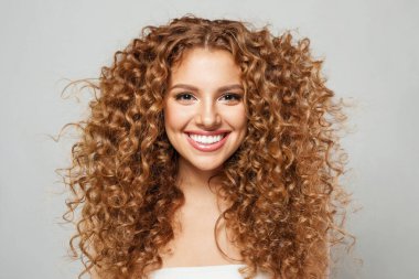 Uzun, sağlıklı saçları ve beyaz arka planda poz veren ipek tenli, gülen genç bir kadın. Moda stüdyosu portresi