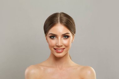 Beyaz arka planda poz veren taze ipek tenli zarif genç bir kadın. Moda stüdyosu portresi