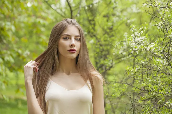 Açık havada muhteşem bir genç bayan. Taze, temiz tenli ve çiçek bahçesinde uzun kahverengi saçlı sağlıklı bir kadın. Seyahat, tatil, sezon ve tatil konsepti