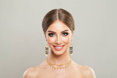 Temiz ciltli, makyajlı ve beyaz stüdyo duvarına karşı mükemmel saç stili olan güzel, sağlıklı bir kadın modeli.