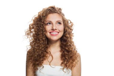 Gülümseyen kızıl saçlı, temiz tenli, kıvırcık saçlı ve doğal makyajlı bir kadın. Beyaz arkaplanda kadın modeli