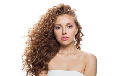 Doğal makyajlı, temiz ciltli ve beyaz arka planda dalgalı saçlı zarif bir genç kadın.