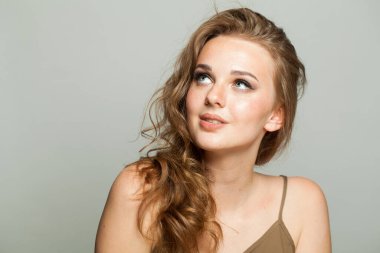 Makyajlı, açık tenli ve beyaz arka planda uzun dalgalı saç modeline bakıyorum. Moda stüdyosu genç bir kadının portresi.