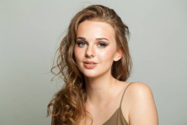 Makyajlı, pürüzsüz ciltli ve beyaz arka planda uzun dalgalı saç stili olan güzel bir kadın modeli. Moda stüdyosu genç bir kadının portresi.