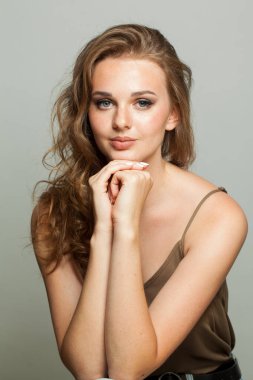 Makyajlı, pürüzsüz ciltli ve beyaz arka planda uzun dalgalı saç stili olan sevimli bir kadın modeli. Moda stüdyosu genç bir kadının portresi.