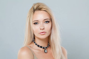 Makyajlı, uzun sarı saçlı, beyaz stüdyo duvarlı genç bir kadının güzel portresi.