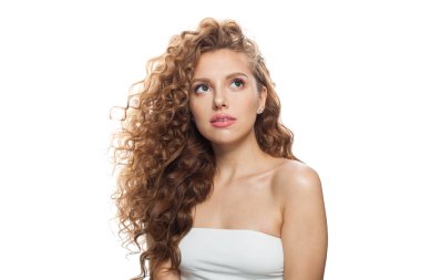 Çekici, güzel, kızıl saçlı, temiz tenli, kıvırcık saçlı ve doğal makyajlı bir kadın. Beyaz arkaplana bakan kadın modeli